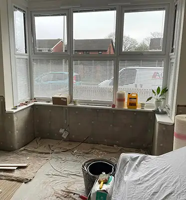 Before: A bay window with the old plaster stripped back to damp-proof membrane
