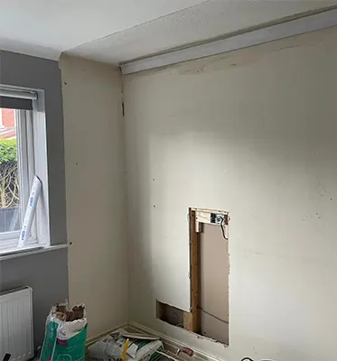 Before: A bedroom wall with damaged old plaster and a hole cut through it